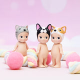 Three figurines from the Sonny Angel Animal Version 3 Series stand among colorful marshmallows and pink balls on a pastel background, captivating collectors with their charm.