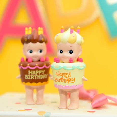 Amidst the lively atmosphere of a festive celebration, uncover two delightful Sonny Angel figurines of babies cozily seated in birthday cakes—one adorned with luscious chocolate icing and the other with smooth vanilla. These charming figures are part of the Sonny Angel Happy Birthday Cake Gift series, offering a surprise reminiscent of opening a Blind Box.