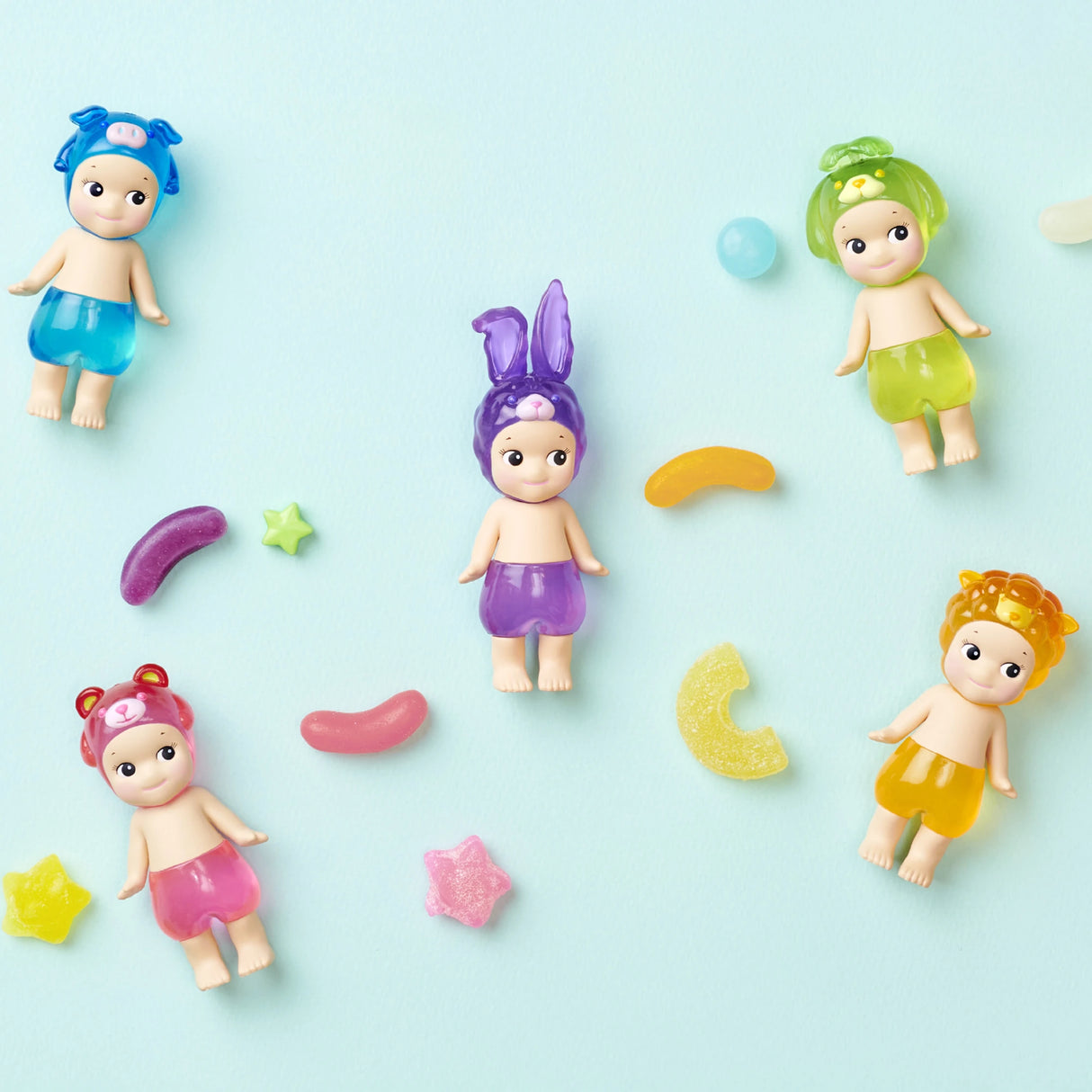 Five Sonny Angel figures from the Candy Store Series, each wearing charming animal hats, are arranged on a light blue background alongside playful candy shapes.