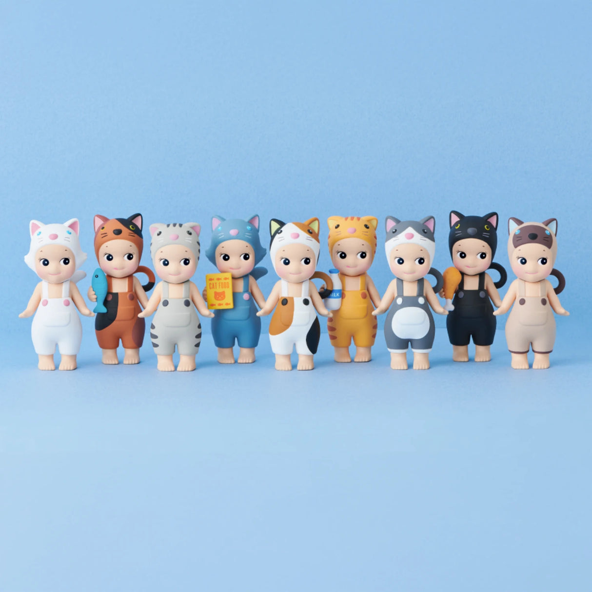 Nine toy figures from the Sonny Angel Cat Life Series by Sonny Angel, each outfitted in cat-themed costumes with a variety of colorful patterns, charmingly pose against a light blue backdrop.