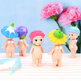 Five small figures from the Sonny Angel Flower Series by Sonny Angel are elegantly positioned on a striped surface, with pink flowers blooming in the background.