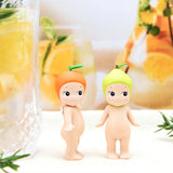 Two adorable Sonny Angel figurines from the Fruit Series Blind Box, each wearing citrus-themed hats, stand beside a glass of lemon juice, with a vibrant fruit design background adding to the charm.