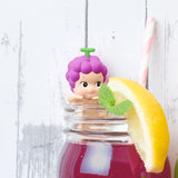 A whimsical scene featuring a Sonny Angel figure from the Hippers Harvest Series comes to life as a purple-haired collectible peeks over the rim of a jar filled with vibrant purple juice, accented by a lemon slice and mint sprig. A striped straw completes this delightful display, perfect for fans of Sonny Angel's charming creations.