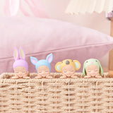 Four small figures from the Sonny Angel Hippers Blind Box - Dreaming each feature delightful animal-themed hats—rabbit, bear, koala, and frog—and are charmingly placed on a woven basket in front of a pink pillow.