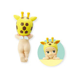 Introducing the Sonny Angel Hippers Blind Box - Animals by Sonny Angel: This adorable toy figure features a baby wearing a giraffe hat. It is displayed with both a back view and a front view framed in a circle, highlighting its charming face and hands. The figure comes with reusable adhesive, allowing you to place it anywhere you desire effortlessly.