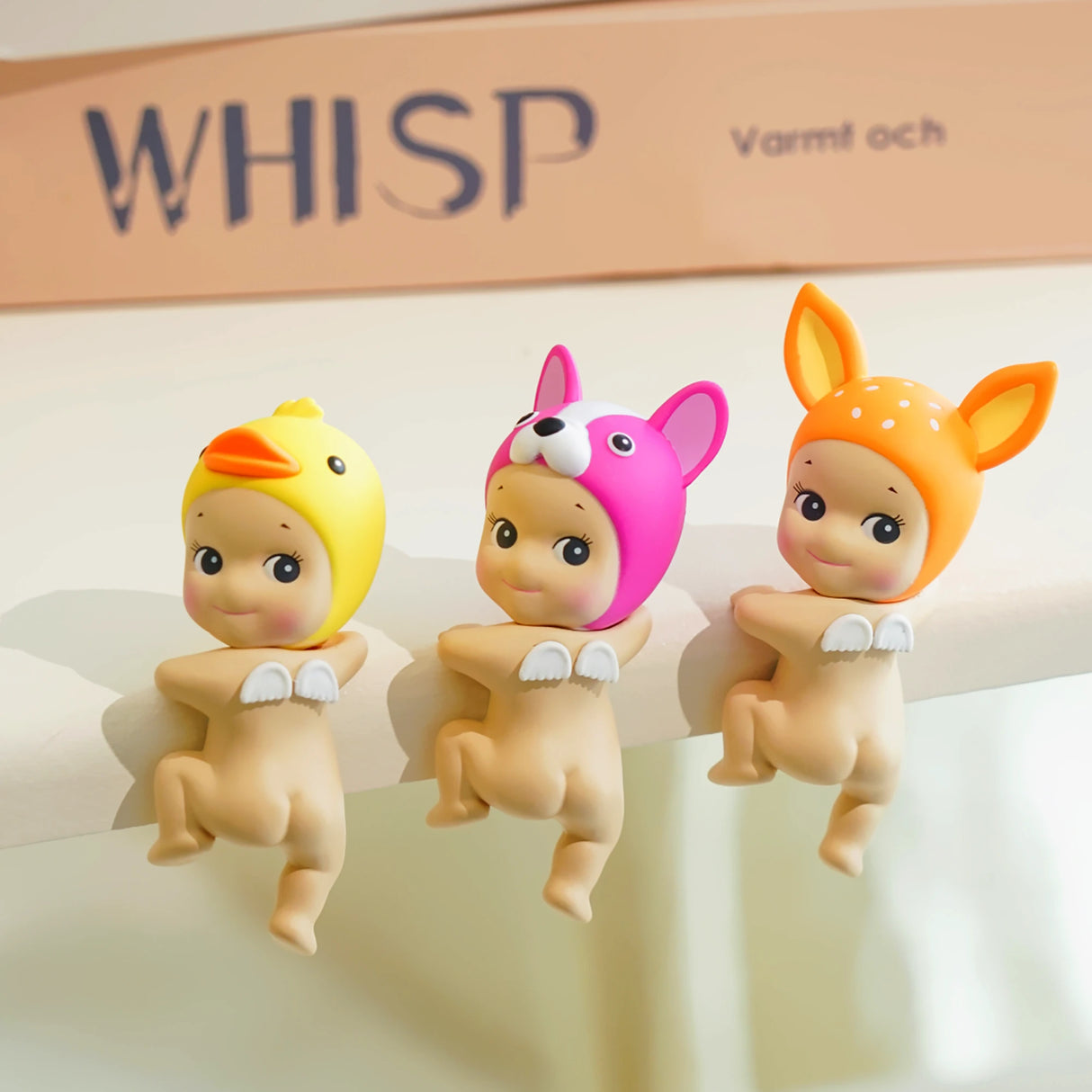 Three small Sonny Angel Hippers, from the Looking Back series, sit on a ledge, each wearing an animal-themed hat: a duck, a rabbit, and a deer. These collectible figures by Sonny Angel bring charm and whimsy to any space.