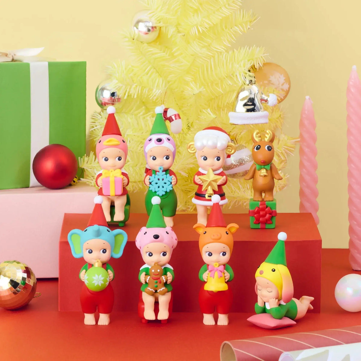 Group of mini elf-themed vinyl figures on display steps beneath a yellow tree