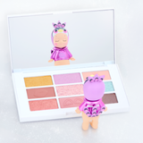 Makeup Angel figure posed in front of an open eyeshadow palette and compact set