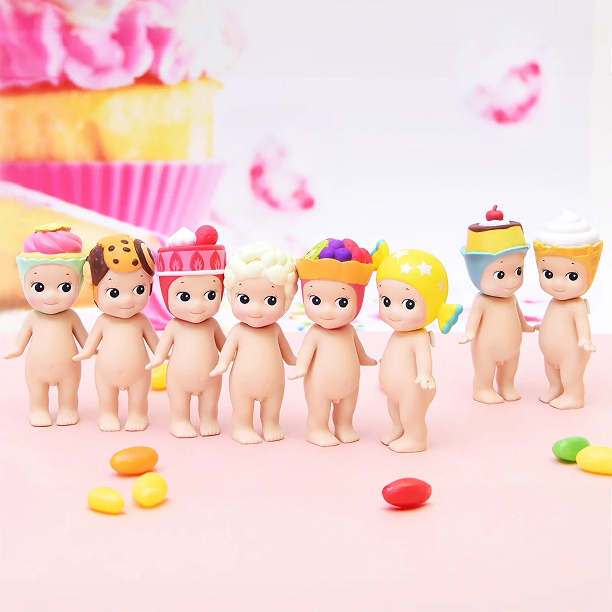 Seven collectible figures from the Sonny Angel Sweets Series Blind Box are lined up, each adorned with dessert-themed hats. Vibrant candies are strewn about, suggesting the delightful surprises that come with every Sonny Angel blind box.