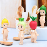 Four figurines from the Sonny Angel Vegetable Series Blind Box, each with colorful vegetable-themed hats, stand on a surface surrounded by wooden spoons and a basket in the background.