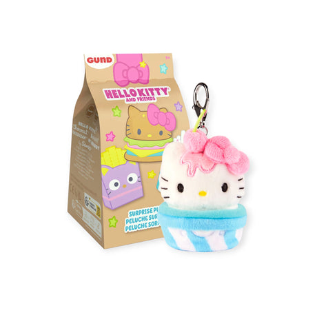 The Hello Kitty Snack Plush - Blind Bag features a charming plush cupcake keychain with a pink bow, nestled in front of a decorated box adorned with cartoon characters and colorful stars. A delightful addition to any Hello Kitty keychains collection.