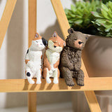 A cat, fox, and bear figurine sit side by side on a wooden ledge with a potted succulent behind them, capturing the essence of the Sleepy Animals Blind Box by Yell. Collect all five to complete your Relaxing Desk Friends collection!