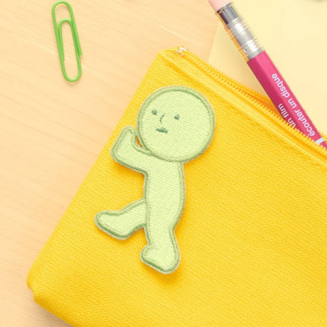 Yellow fabric embroidery patch with green character in a pushing pose