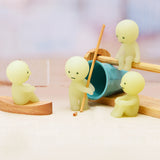 Smiski Series 1 - Blind Box figures, inspired by the playful designs from the Smiski brand, come to life with wooden props and a blue cup on a light surface.