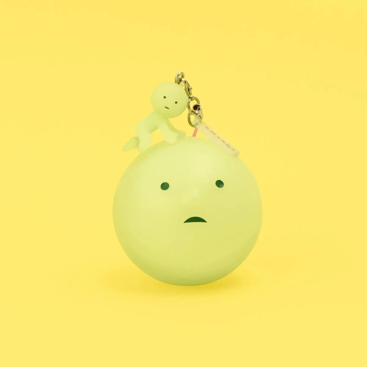 Yellow-green Smiski keychain figure on a round charm with metal clasp