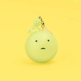 Yellow-green Smiski keychain figure on a round charm with metal clasp