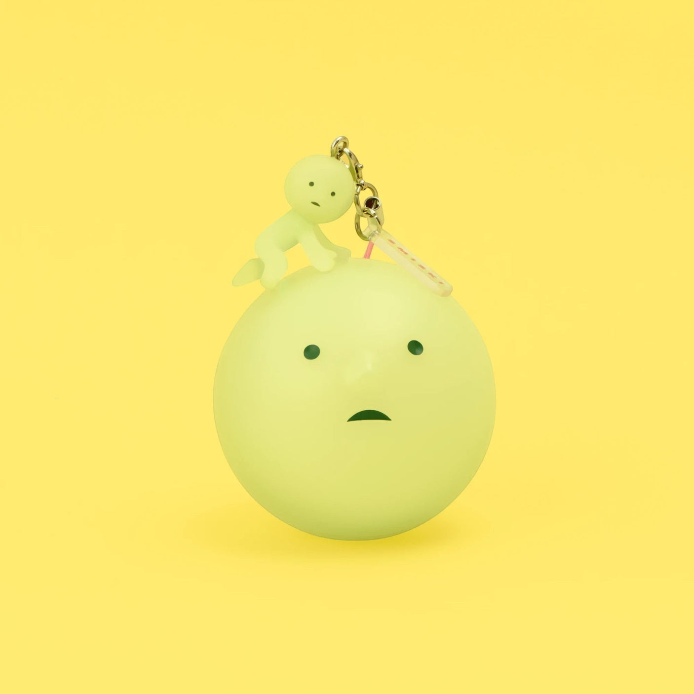 Yellow-green Smiski keychain figure on a round charm with metal clasp