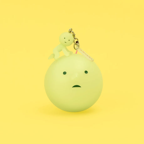 Yellow-green Smiski keychain figure on a round charm with metal clasp