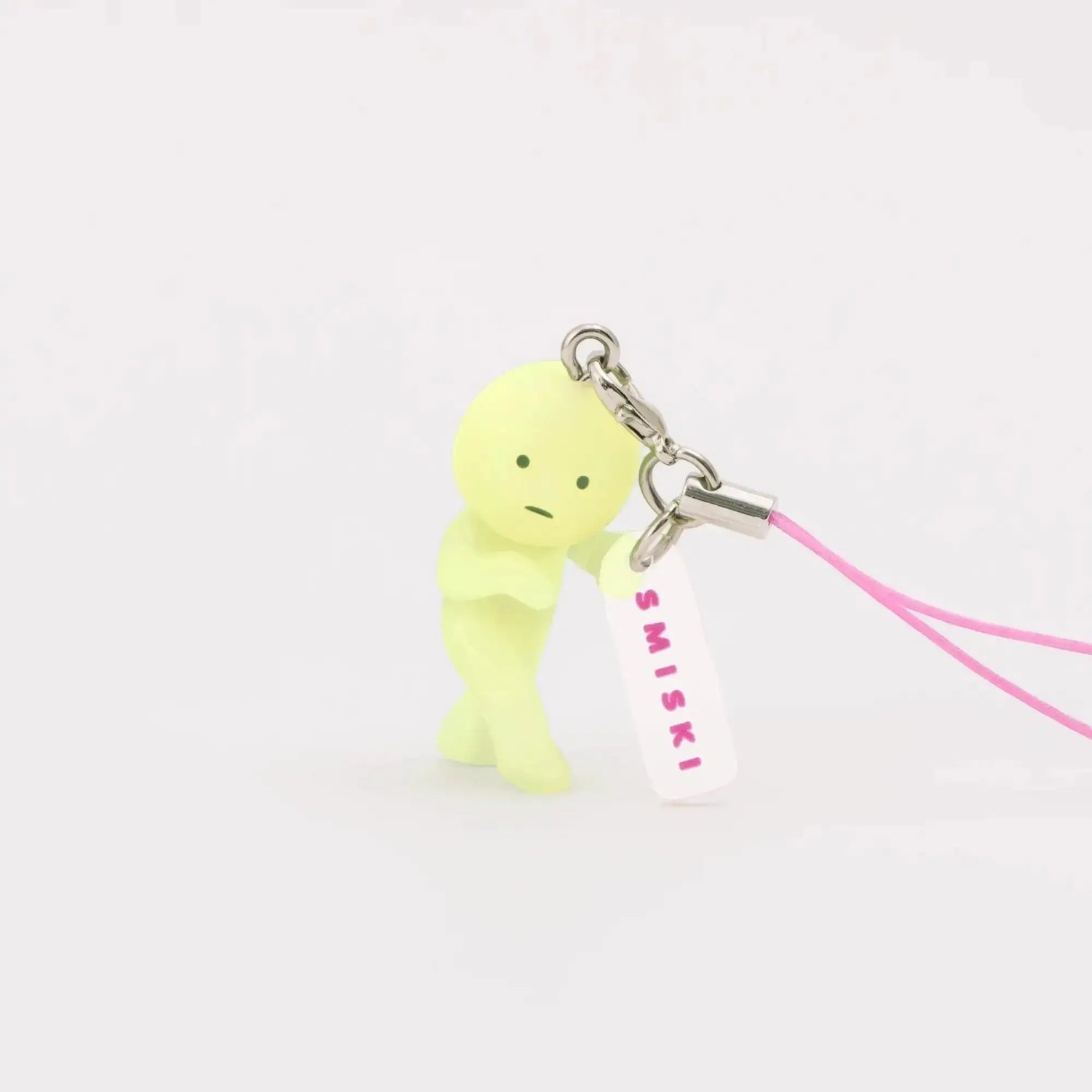 Lemon-green Smiski keychain figure with pink lanyard strap and small charm tag