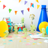 Smiski Cheer Series - Blind Box figures and musical instruments are displayed on a table with colorful bunting above. Confetti and a blue megaphone add to the festive atmosphere, evoking the mystery and excitement of an intriguing blind box reveal.