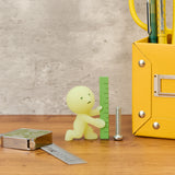 Smiski construction figure holding ruler, light green mini beside yellow toolbox