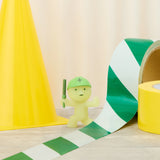 Smiski construction figure in green helmet, light green mini next to green-striped tape roll