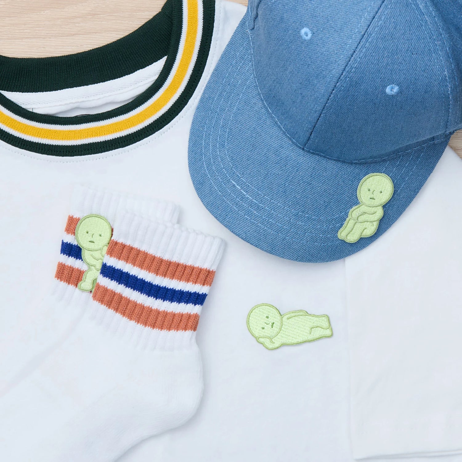 A white T-shirt, white socks with orange and blue stripes, and a blue denim cap—all accessorized with the playful Smiski Embroidery Sticker/Patch by Smiski as an embroidered accent.