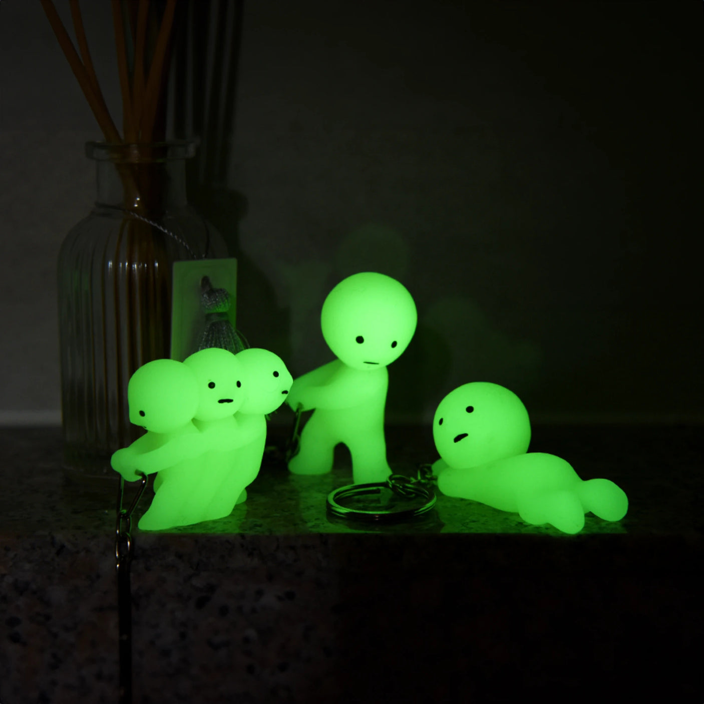 Smiski's Grabbing Key Smiski keychain figure, glowing green, displayed on a dark surface.