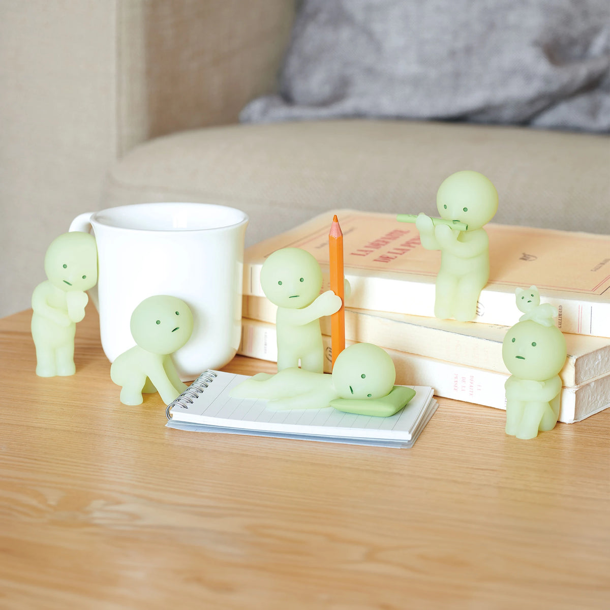 Pale green Smiski blind box figures posed around a desk with books and a mug