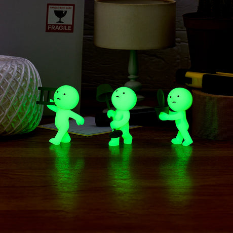 Three Smiski Moving Series figures from a Blind Box clutch gardening tools as they line up on a wooden surface, nestled among a rope and various office supplies.