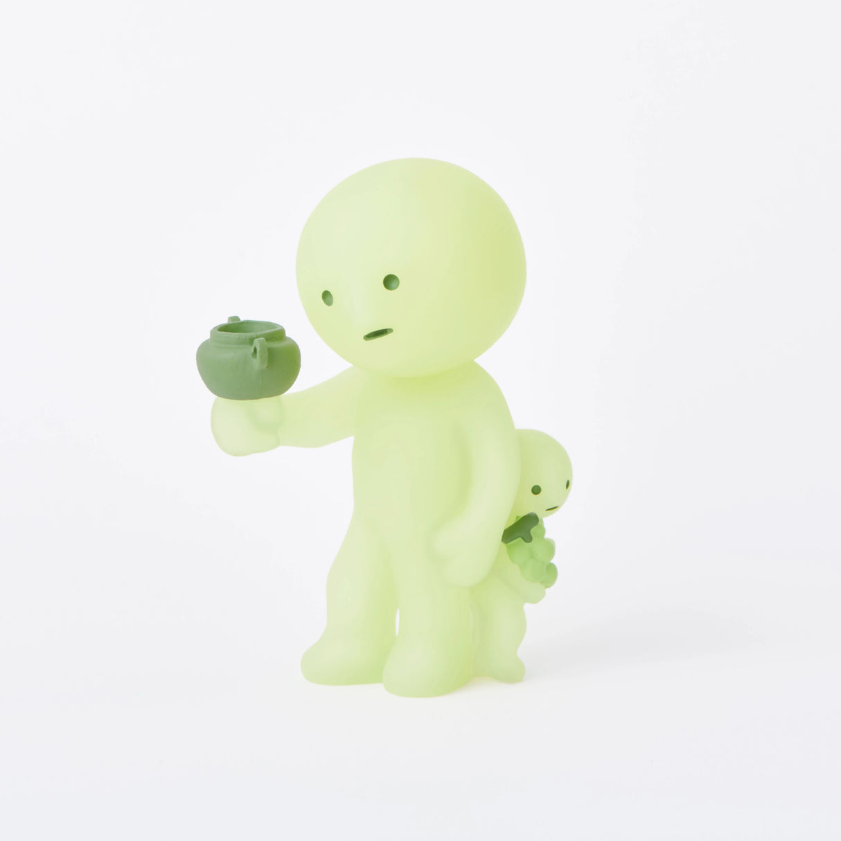 In the Smiski Museum Series - Blind Box by Smiski, two small green humanoid figures come to life, with the larger figure holding a pot and the smaller one carrying a leaf. These glow-in-the-dark companions add a whimsical and enchanting touch to any space.