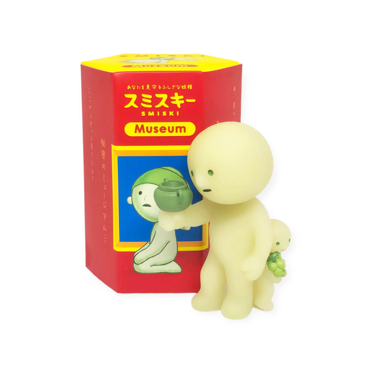 Two small, glow-in-the-dark figures stand near a vibrant red and yellow "Smiski Museum Series - Blind Box." One creative companion holds a small pot, while the other balances a green object on its back, making them intriguing additions to this Smiski collection by the brand.