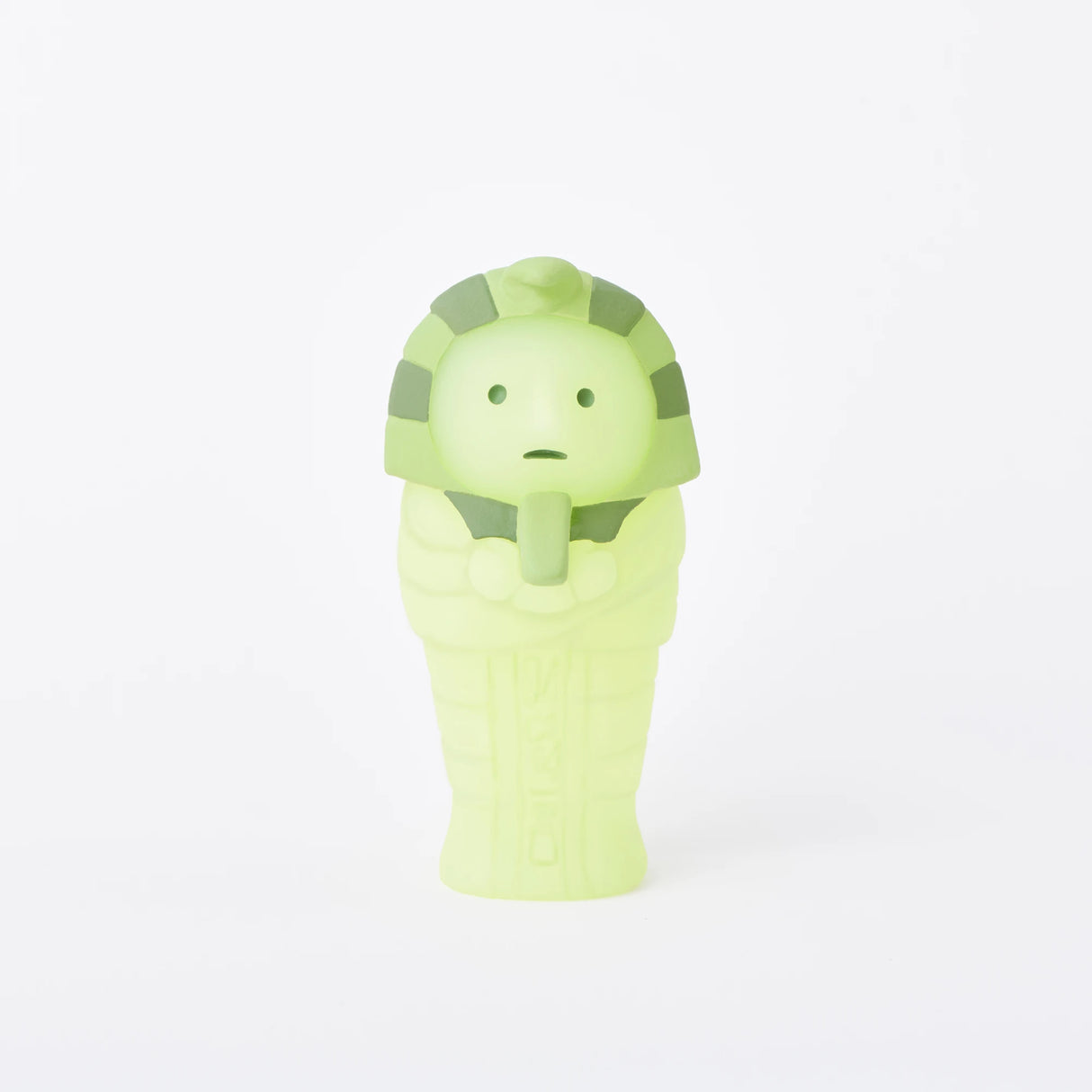 A small, lime-green figure shaped like an ancient Egyptian mummy stands upright on a plain white background, part of the Smiski Museum Series - Blind Box collection, featuring imaginative glow-in-the-dark figures.