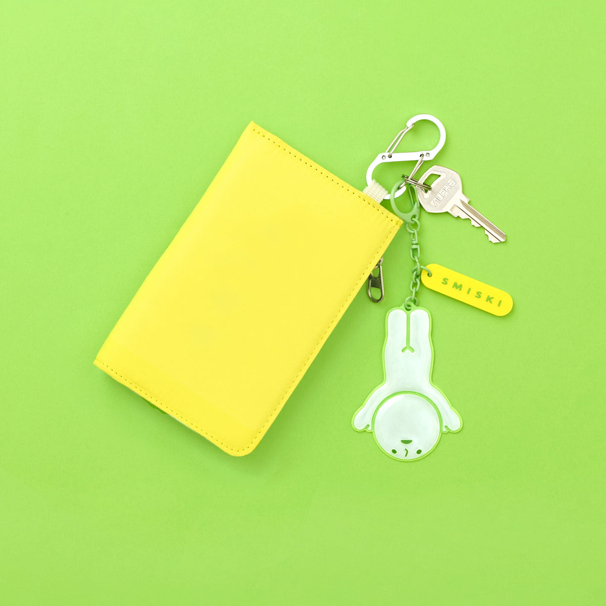 Yellow pouch with reflective green Smiski charm keychain and keyring