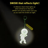 Reflective green Smiski charm glowing in low light on keychain