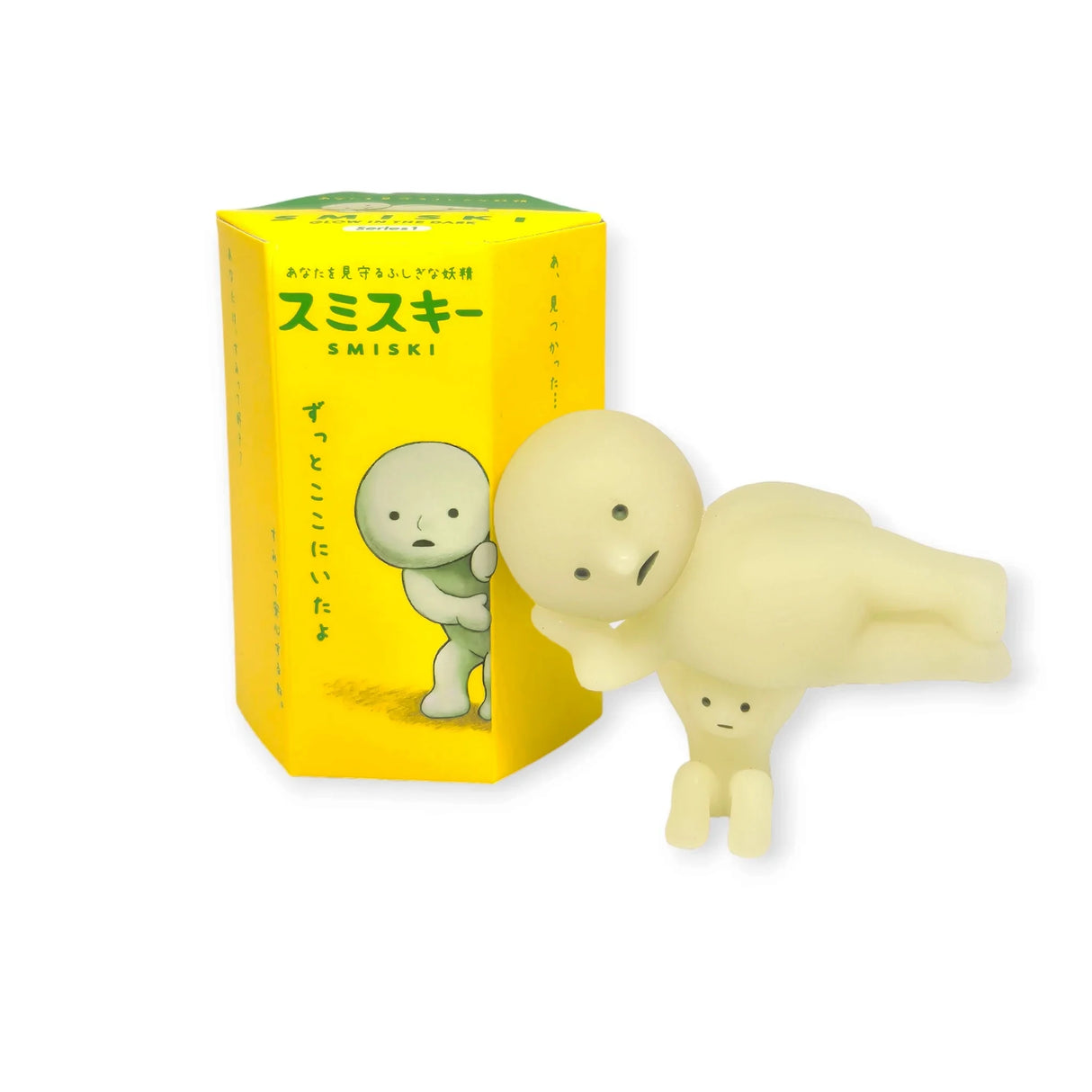 A photo showcasing a Smiski figure from Series 1, accompanied by a bonus 'little Smiski' figure holding it up. Both are displayed next to their Blind Box packaging, highlighting the chance of finding a bonus figure alongside the standard one.