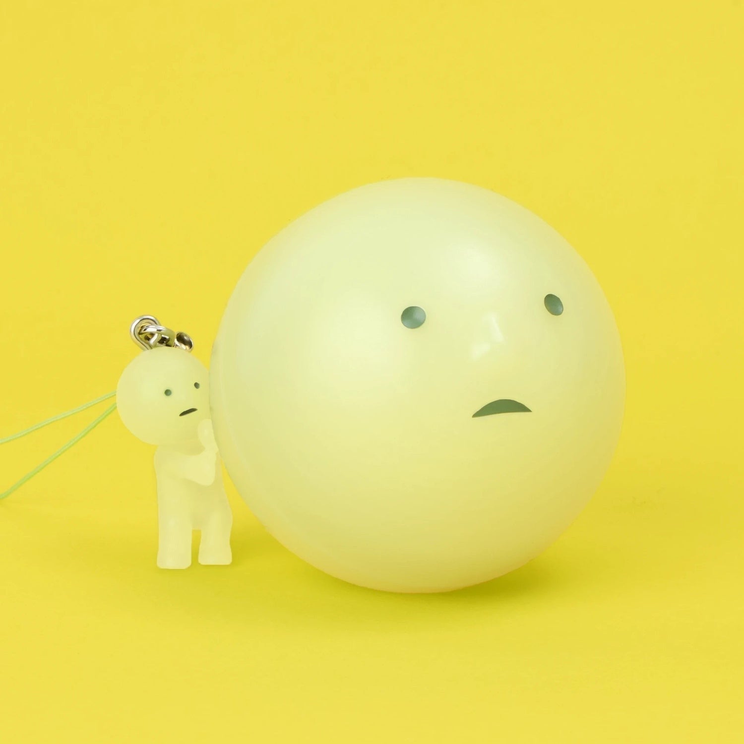 Pale green Smiski-style figure keychain with large ball charm and clip