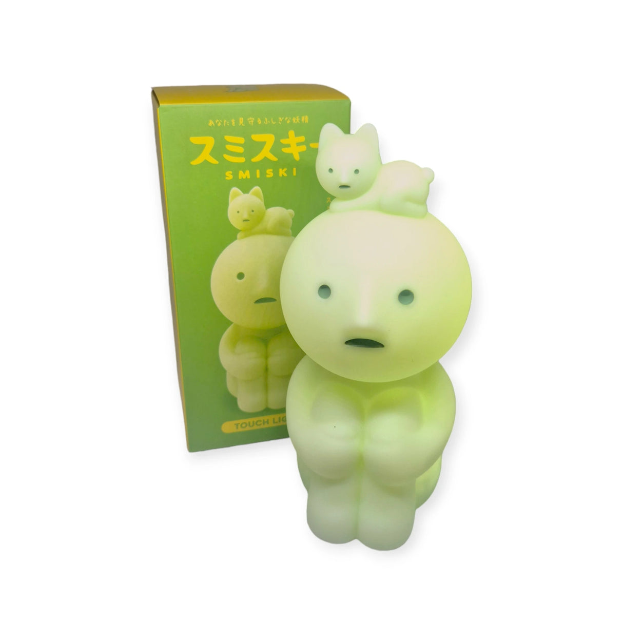 A Smiski Touch Light, featuring a glowing green figurine with a cat-like figure atop its head and functioning as a touch-activated nightlight, is placed next to its matching box labeled "Smiski Touch Light.