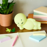 Smiski Touch Light lounging figure, light green, on a desk among stationery