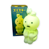 The Smiski Touch Light, from the brand Smiski, is a glowing green touch-activated nightlight featuring a cute figure with an animal on its head, placed next to packaging with Japanese text and imagery.