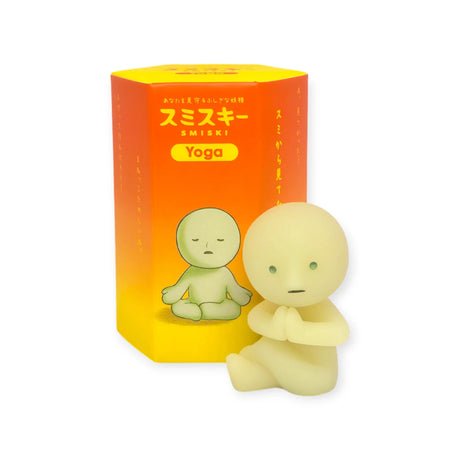 A photo of a Smiski figure from the Yoga Series, performing a twist pose, displayed next to its Blind Box packaging.