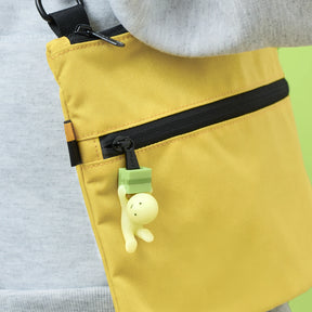 Yellow zippered pouch with pale toy figure hanging from zipper