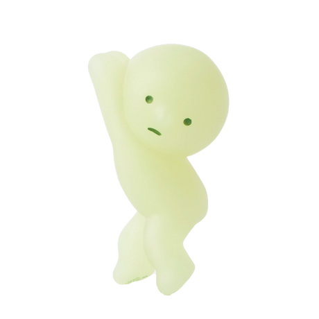 A Smiski ZipperBite - Hanging On, a green, featureless humanoid figure from Smiski, strikes a playful pose with its Glow in the Dark effect making it stand out.