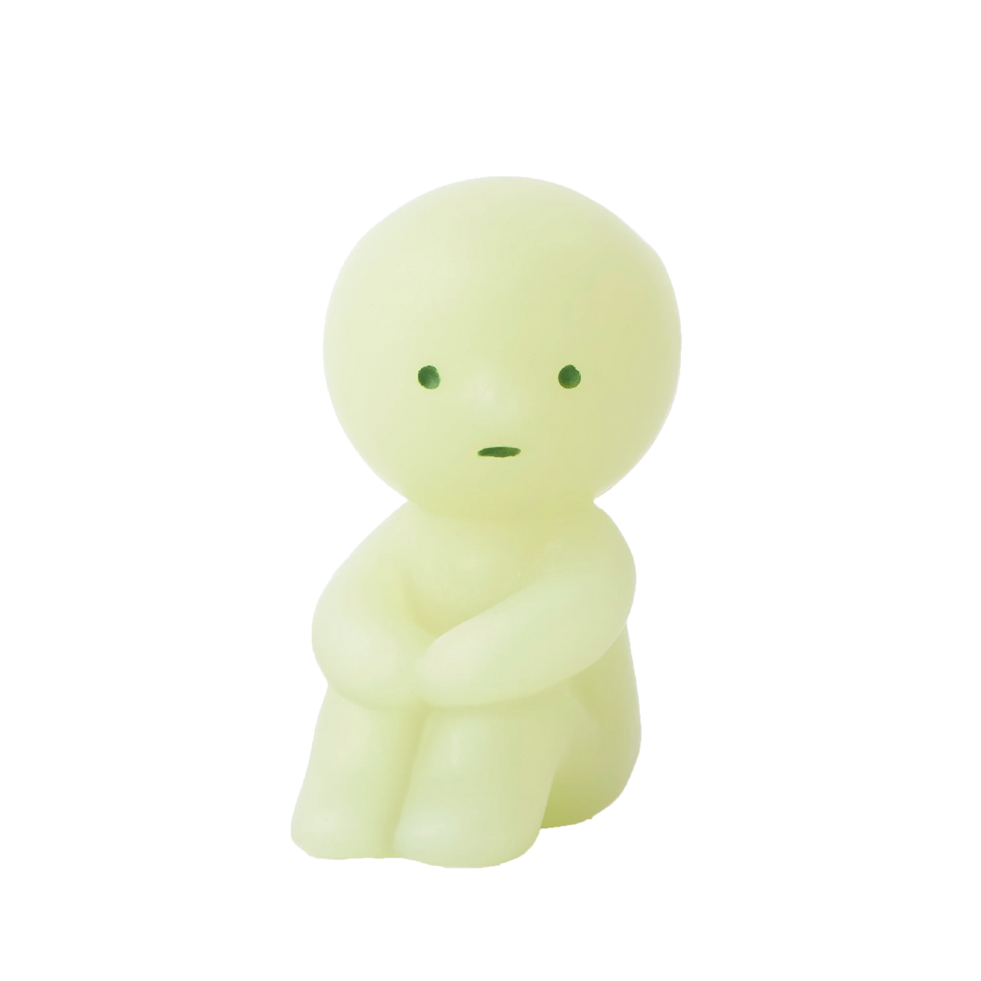 A compact, round-headed figurine in a gentle shade of green sits with its arms resting on its knees and showcases minimal facial features. This Smiski ZipperBite - Hugging Knees from the Smiski brand is a glow-in-the-dark zipper accessory that brings a whimsical charm to your belongings.