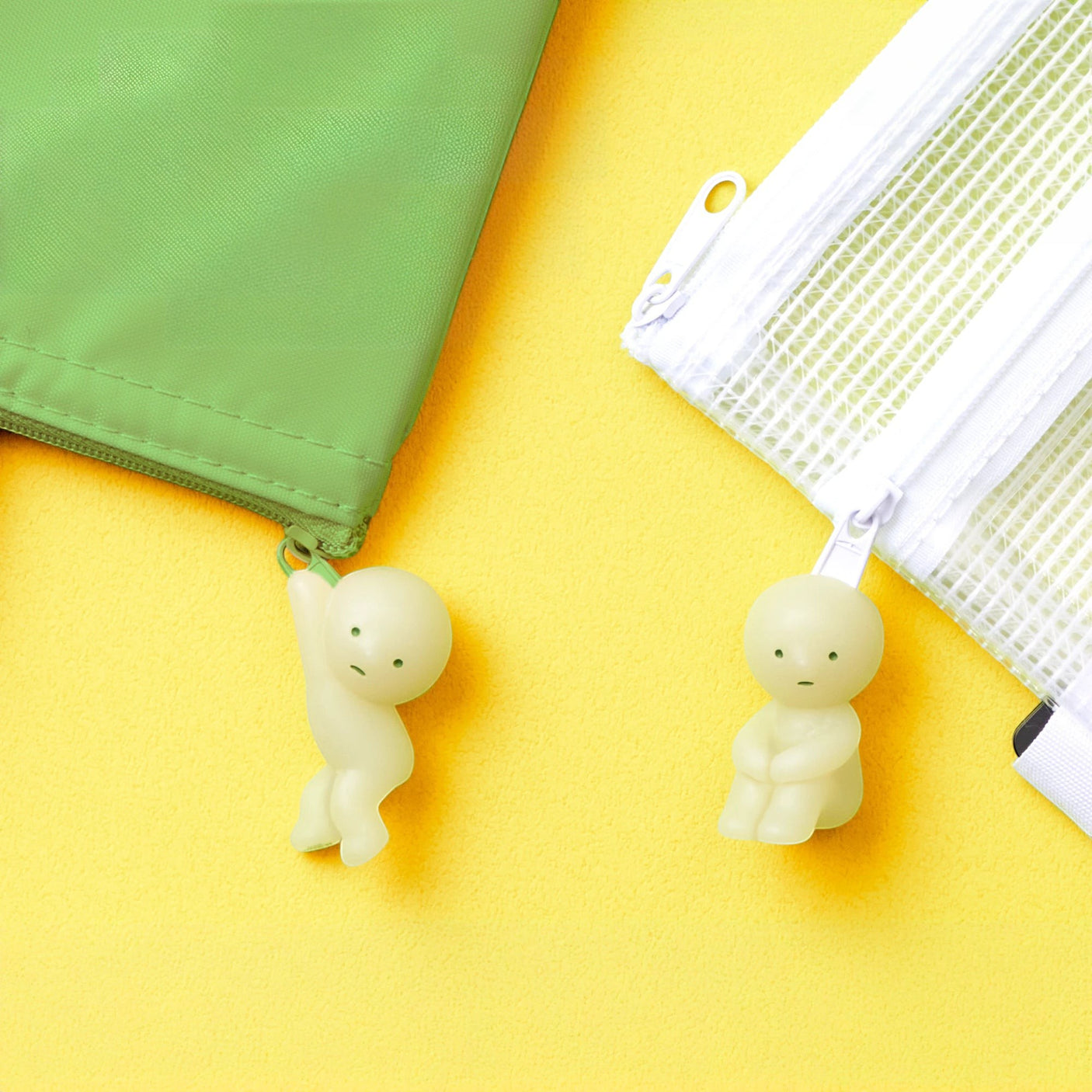 Two small green character zipper pulls attached to a fabric pouch