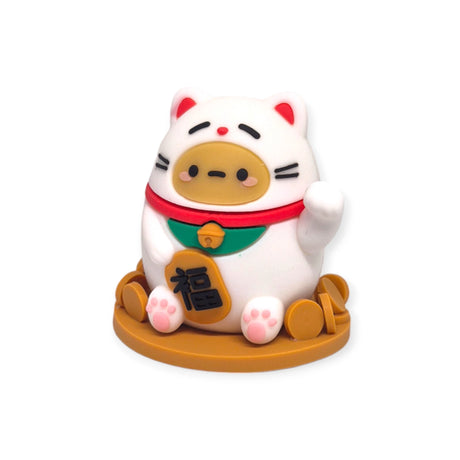 This delightful collectible from Smoko, the Smoko Tayto Potato Cat Blind Box, features a round white cat adorned with a red collar and green bib, holding a gold coin with Asian characters while perched on a circular brown base. It's sure to be treasured by every blind box enthusiast.