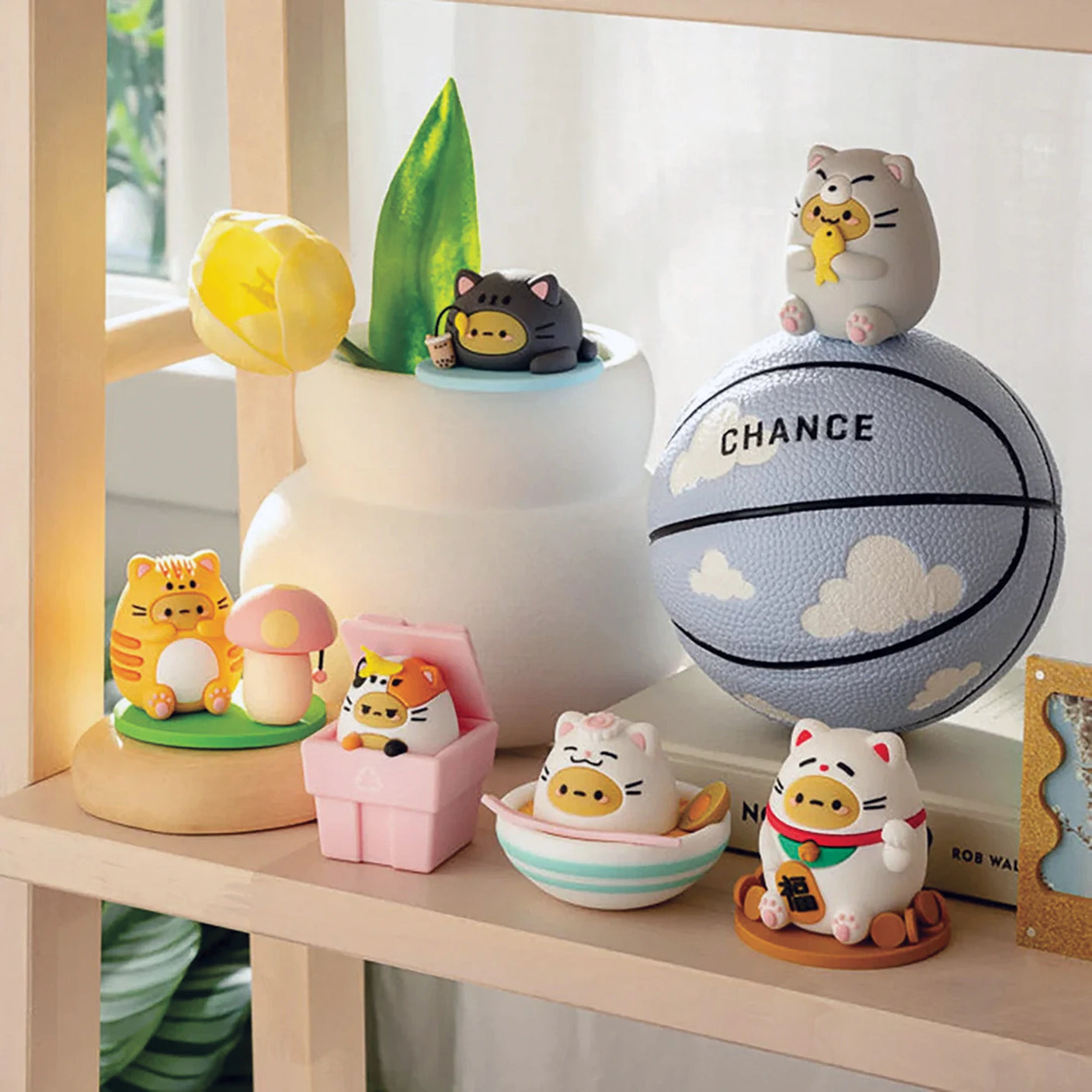 Numerous collectible cat figurines with diverse designs are displayed on shelves, beside a basketball featuring the word "CHANCE." Among these is the rare Smoko Tayto Potato Cat Blind Box, a coveted piece for any passionate collector.