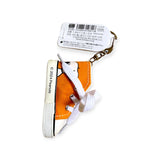 The Snoopy Orange Kicks Keychain is a fun sneaker-shaped accessory with a white sole, featuring a playful cartoon character. It's perfect for Peanuts fans, with a tag in Japanese and English and "© 2022 Peanuts" printed on the shoe, making it an ideal keepsake.