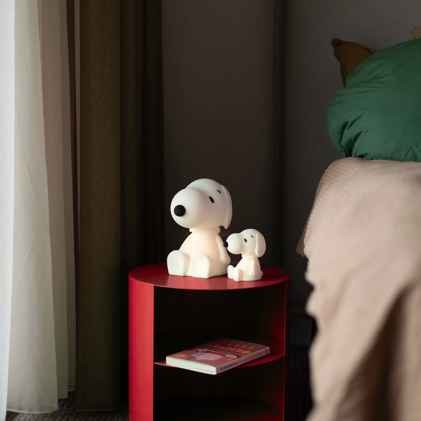 Two dog figurines sit on a red bedside table next to a charming 11cm Snoopy Night Light by Snoopy.