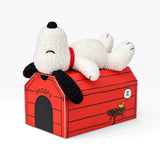 Plush Snoopy dog on red doghouse box, white and black accents, curled pose
